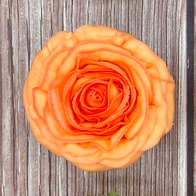 an orange buttercream rose cupcake on a wood surface