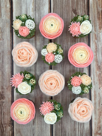 Dozen boxed bloom cupcakes arranged like fresh flowers on wood for wedding dessert table
