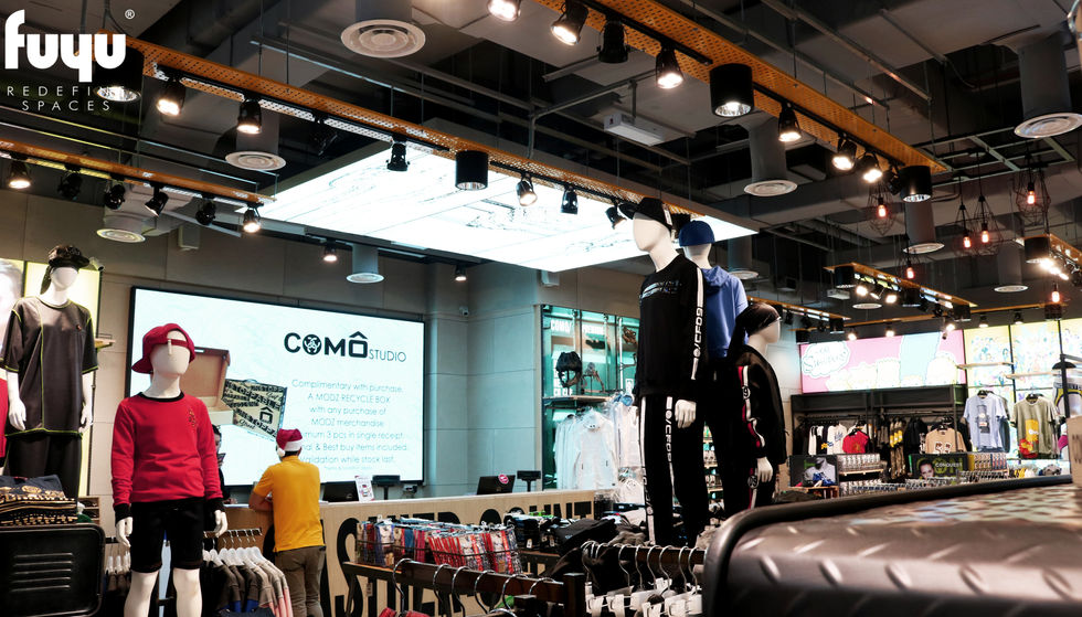 An interior shot of COMO Studio in Sunway Pyramid, designed by Fuyu Dezain Sdn Bhd, showing mannequins wearing sportswear and a screen displaying the COMO Studio brand.
