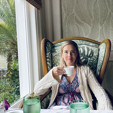 Caroline drinking tea at a cafe, relaxing in a cozy chair
