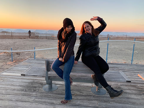 two ladies on beach wearing jackets smiling sunset