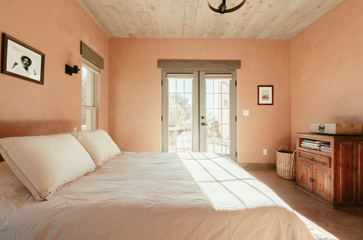 Sunlit adobe bedroom with French doors and natural linen covered queen bed
