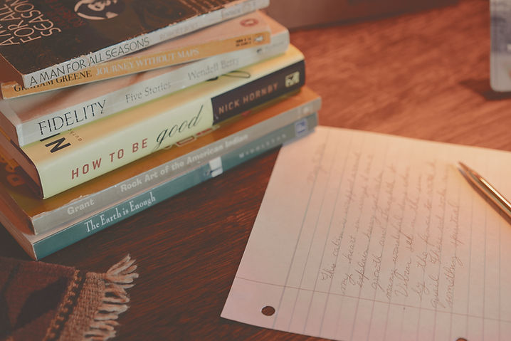 Stack of well-read books beside a handwritten note from Heather Morgan owner of Quiet Shelters, with a pen