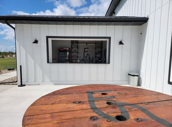 Outdoor wedding cocktail hour setup with spool tables and bar on patio at 5 Family Ranch