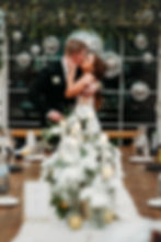 Bride and groom sharing a romantic kiss at their head table, surrounded by elegant decor and glowing candlelight at their Minnesota wedding reception.
