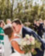 Groom kissing the bride at the end of their outdoor ceremony, surrounded by blooming florals during a beautiful spring wedding in Minnesota.