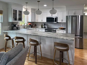 Kitchen peninsula and bar stools in refaced kitchen with white shaker cabinets.