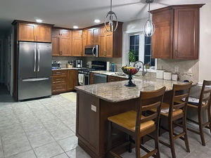 Newly refaced kitchen in Dracut, MA, showcasing a spacious island and elegant wooden cabinets for a warm, welcoming look.