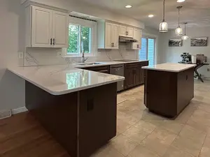 Elegant kitchen with white and dark shaker cabinets, featuring a large island and a marble countertop.