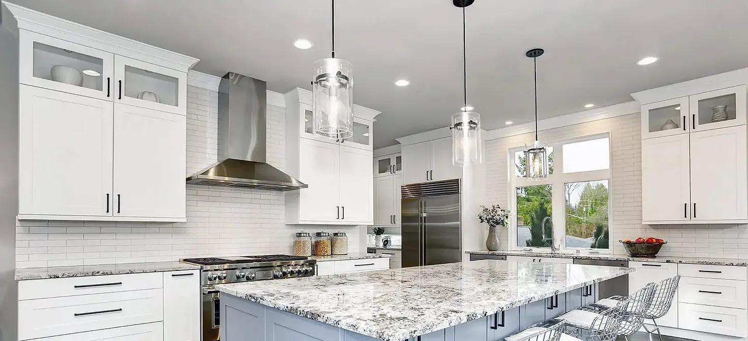 Elegant kitchen with white cabinetry, a large island, and stainless steel appliances, showcasing contemporary luxury design.