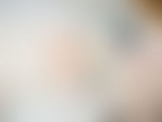 Woman choosing a pink cabinet door sample in a showroom with marble background. Various color samples and handles are on the counter.