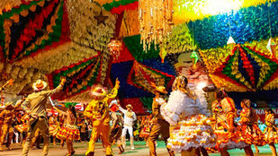 Imagem representando festas juninas no Brasil com bandeirinhas, fogueira e público em celebração típica do São João