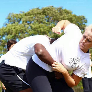 Mulher treinando Krav Maga com instrutor, praticando técnica de defesa pessoal