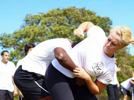 Mulher treinando Krav Maga com instrutor, praticando técnica de defesa pessoal