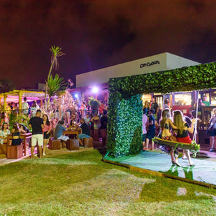 Palco iluminado do Café Curaçao com público reunido em noite de verão em Guaratuba