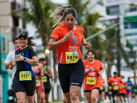 Mulheres correndo em prova de rua com cenário urbano e clima esportivo