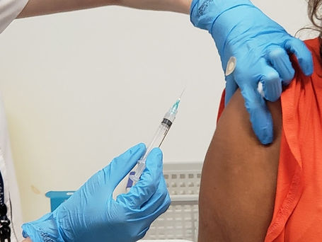 Profissional de saúde aplicando vacina contra dengue em sala de imunização