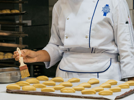 Pães artesanais dourados e viennoiseries em bancada de confeitaria profissional