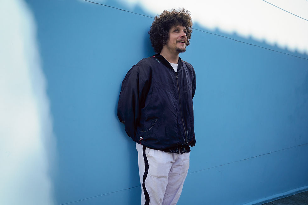 Chico Chico cantando ao vivo no palco, iluminado em tons quentes, durante turnê