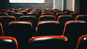 Fileiras de poltronas vermelhas em uma sala de cinema vazia