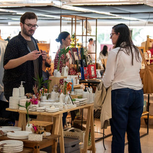 Público caminhando entre estandes coloridos do Quintal do Lupa no Museu Oscar Niemeyer em Curitiba.