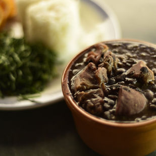 Feijoada servida em panelas de barro com acompanhamentos tradicionais na mesa