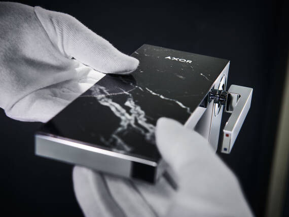 Gloved hands installing a black marble AXOR MyEdition cover.