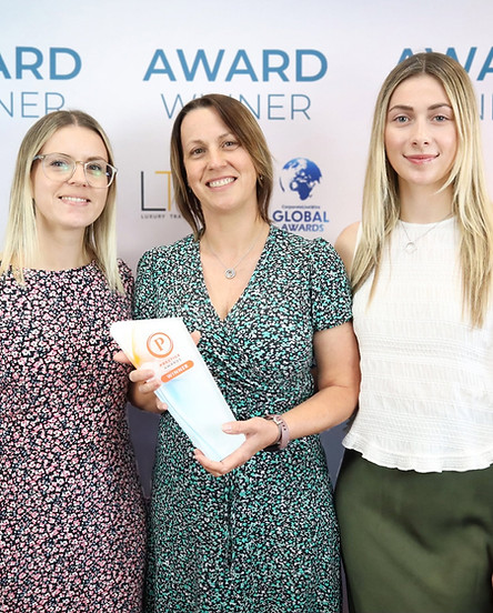 3 ladies stood smiling with an award