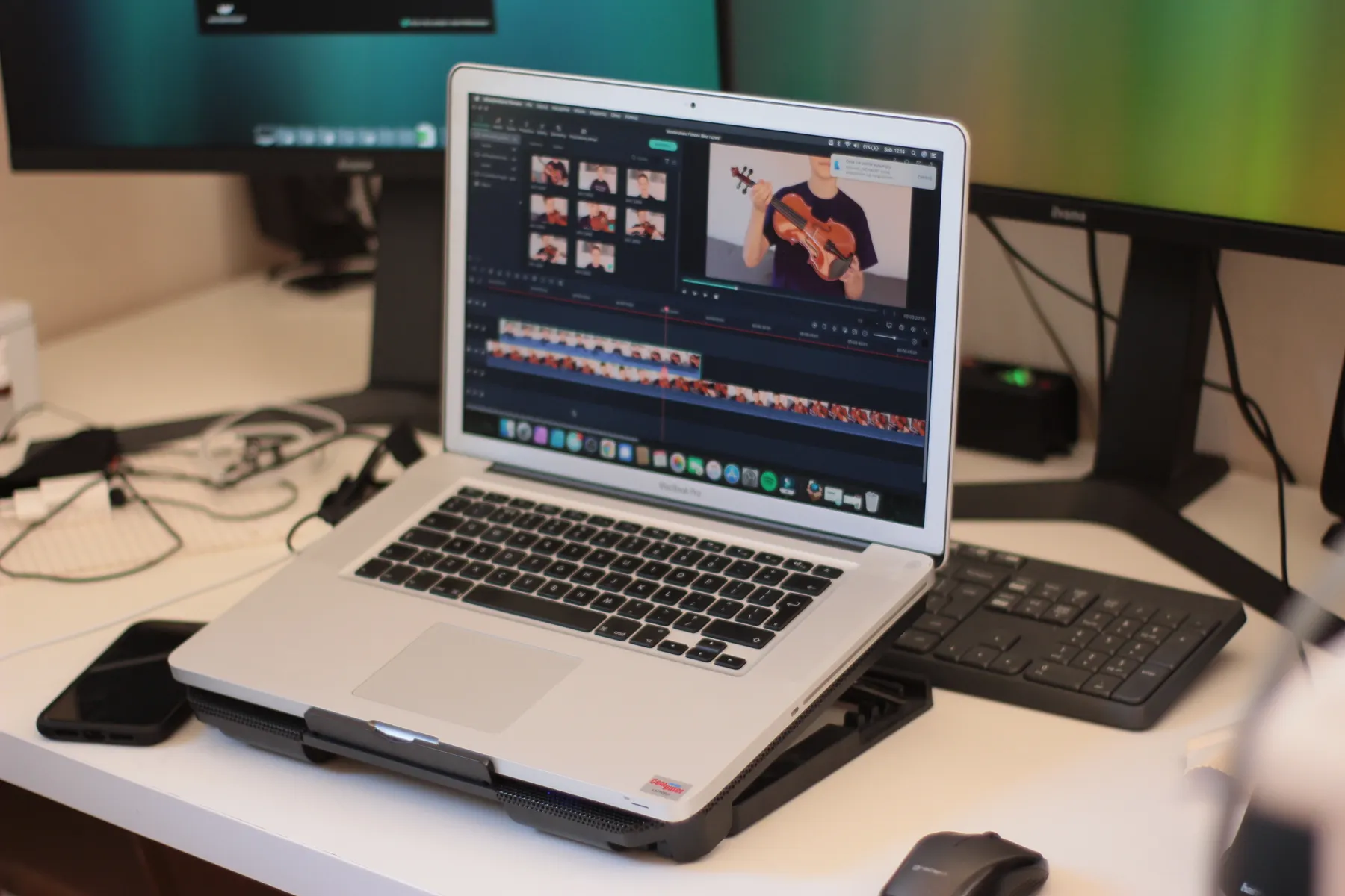 A laptop displays video-editing software on a desk.