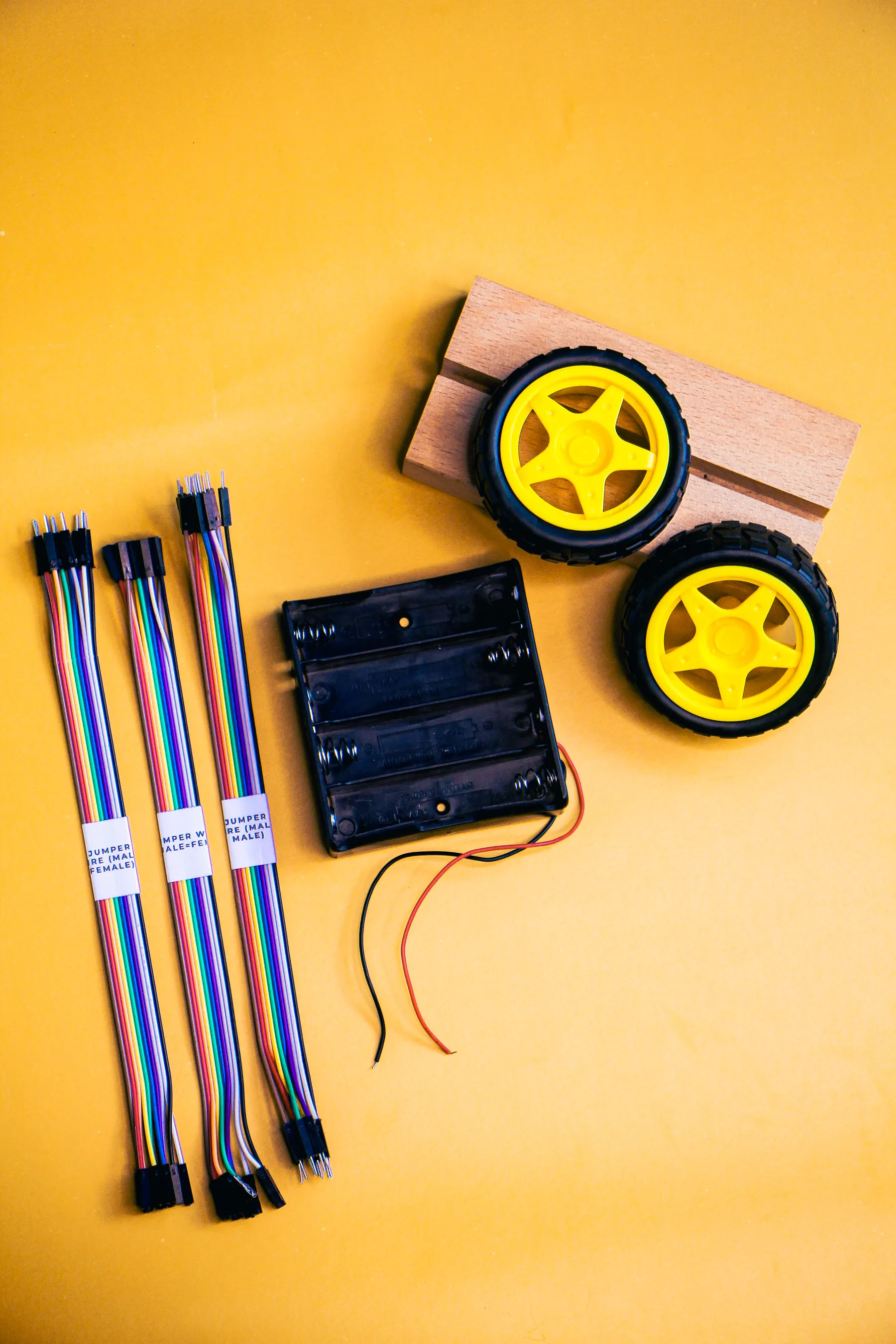 Robot wheels, motors and wires are laid out on a table.