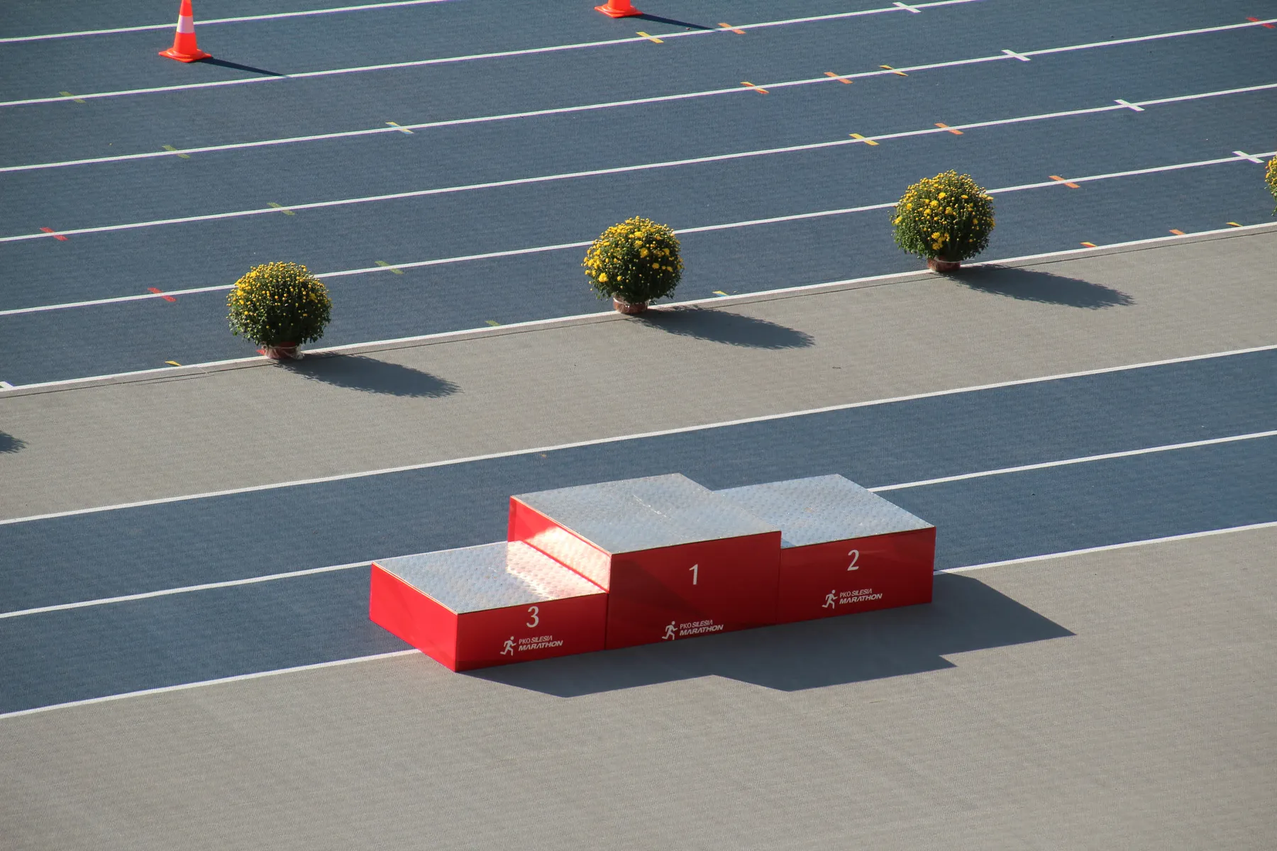 An empty winners podium stands beside an athletics track.