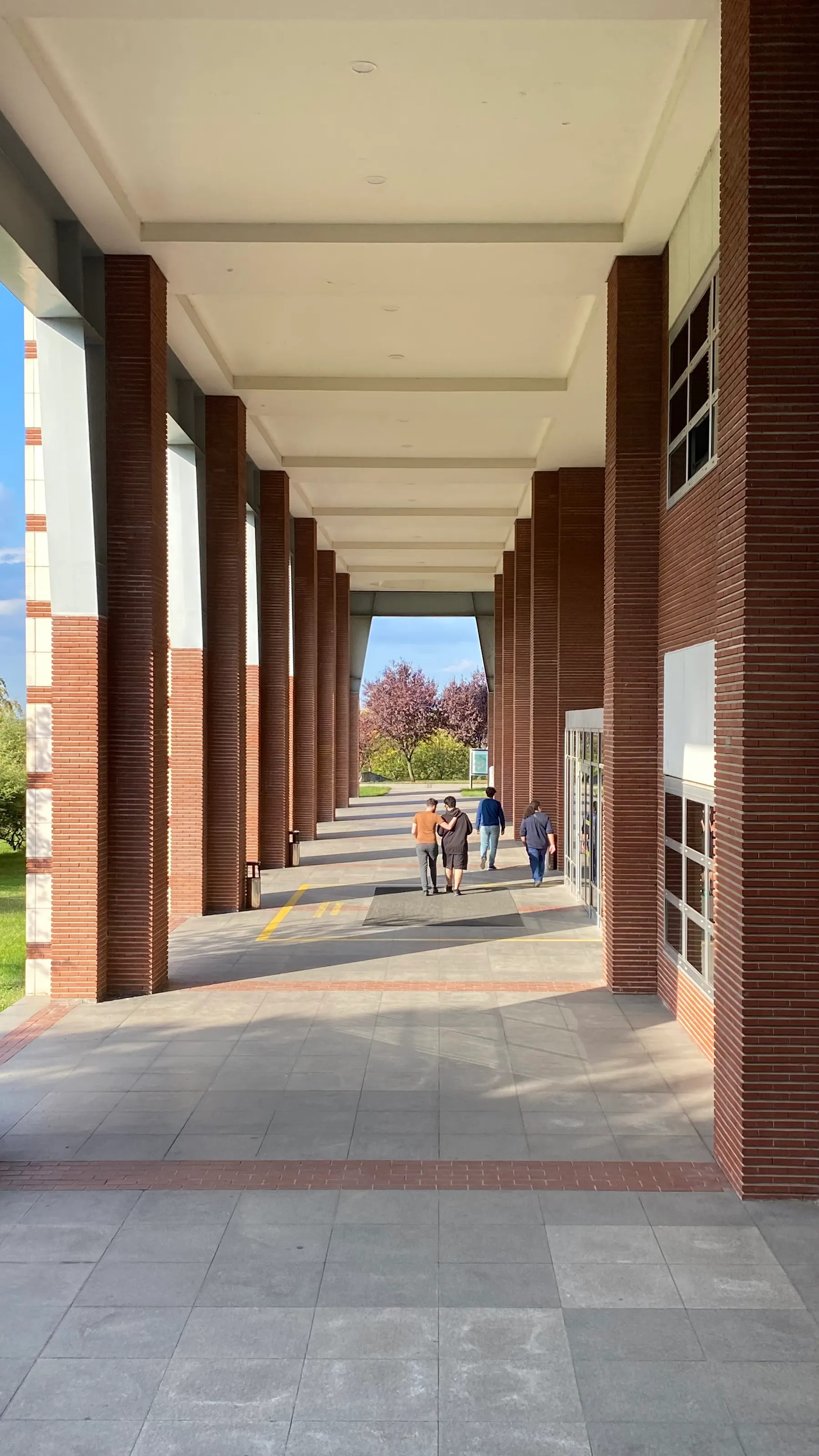 People walk through a sunlit university campus.
