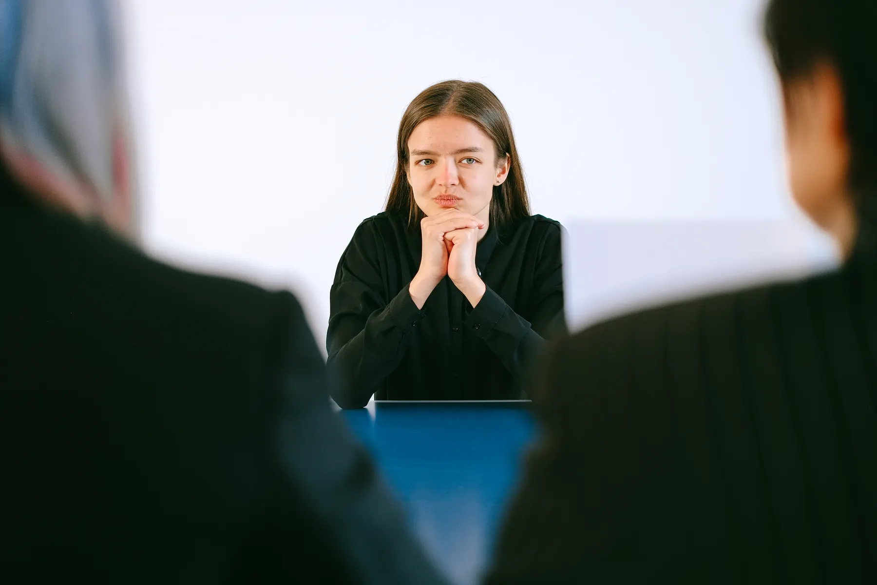 A job candidate sits opposite interviewers at a table.