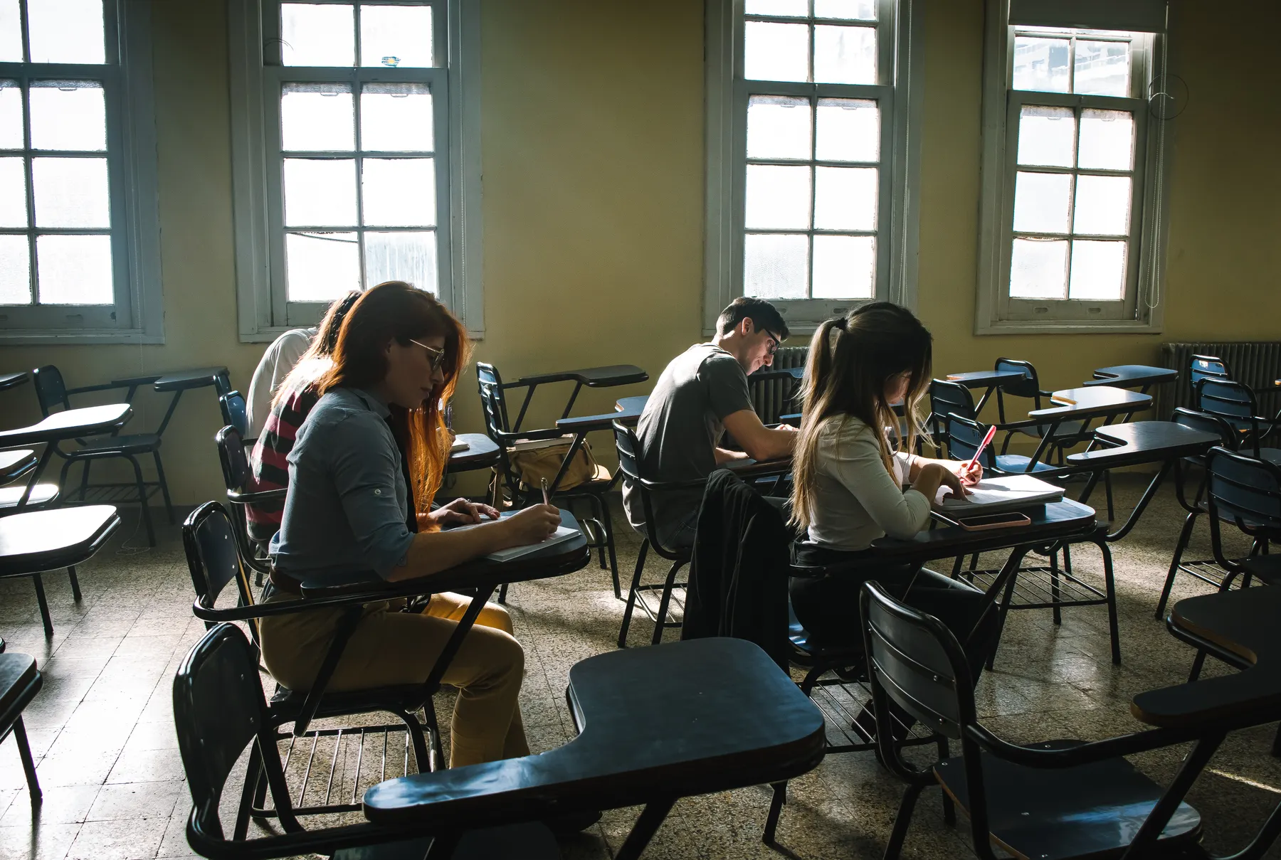 Students write during an examination in a classroom.