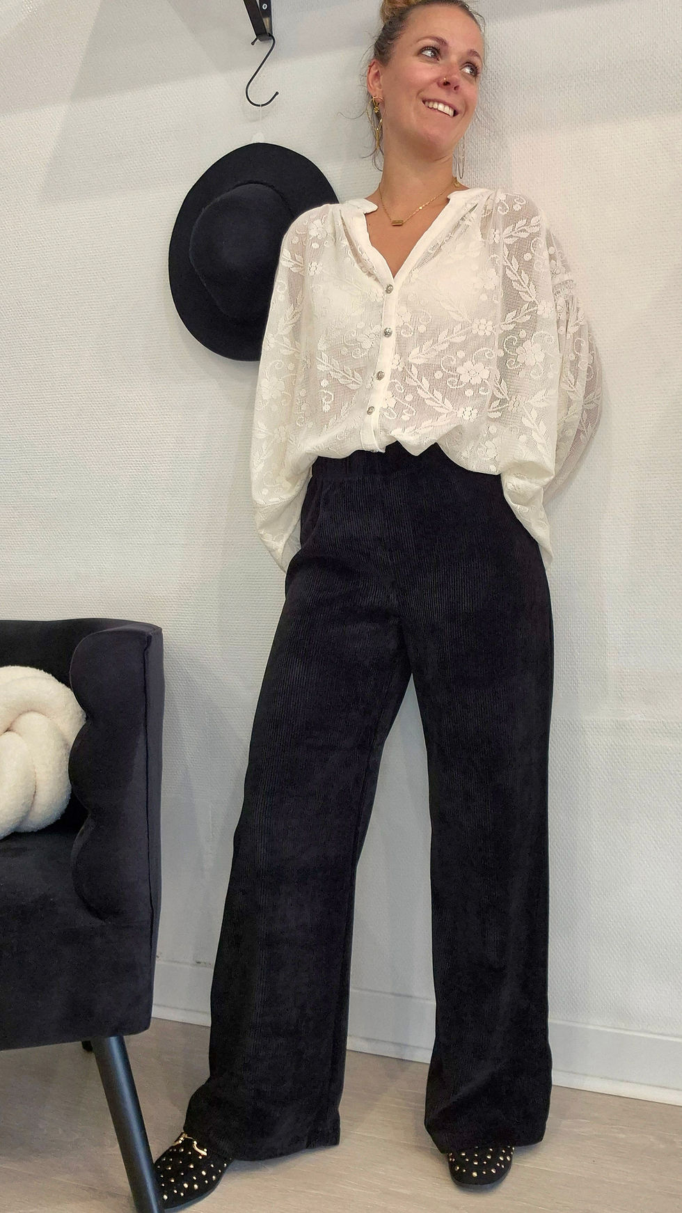 Pantalon en velours côtelé noir coupe droite porté avec une blouse élégante.