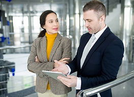 Professional man and woman walking and talking in a hallway with a tablet