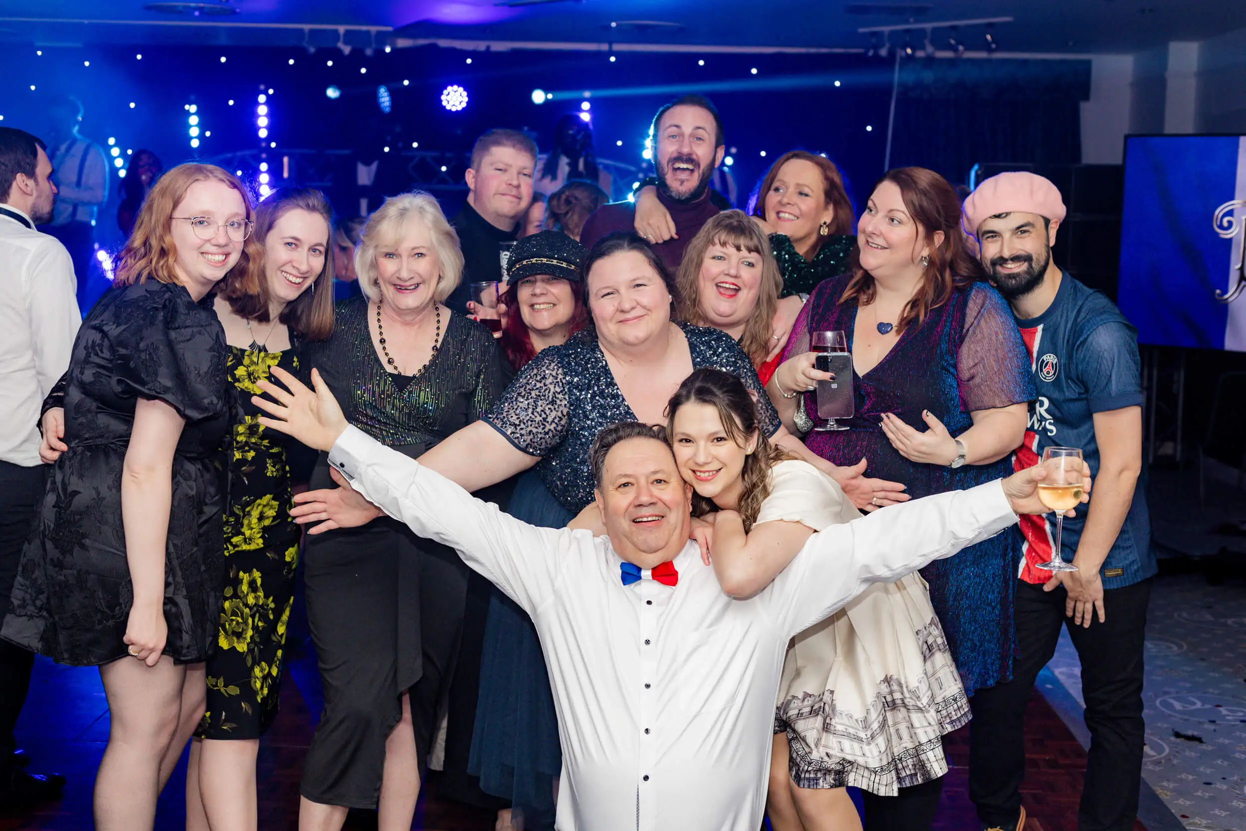 A group photo of attendees posing together, smiling brightly during the Paris-themed celebration.
