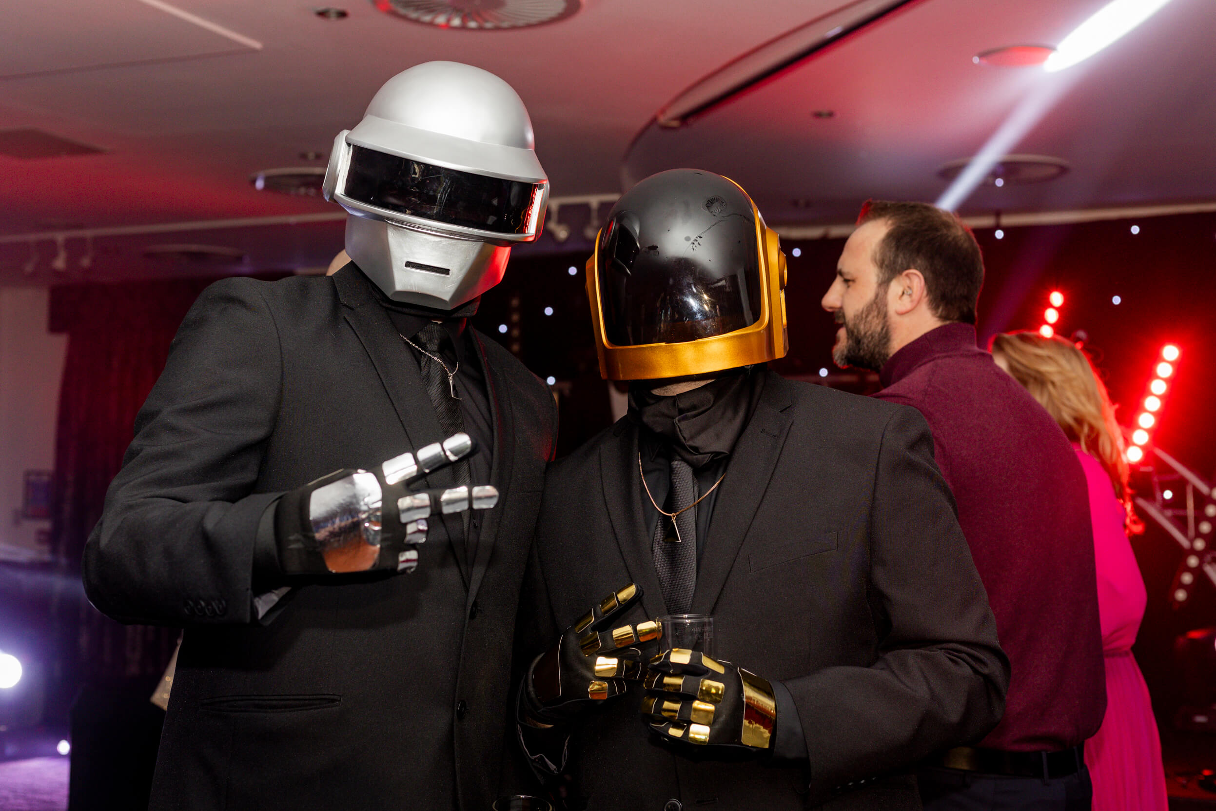 Two individuals dressed as Daft Punk with metallic helmets and gloves, adding a playful touch to the theme.
