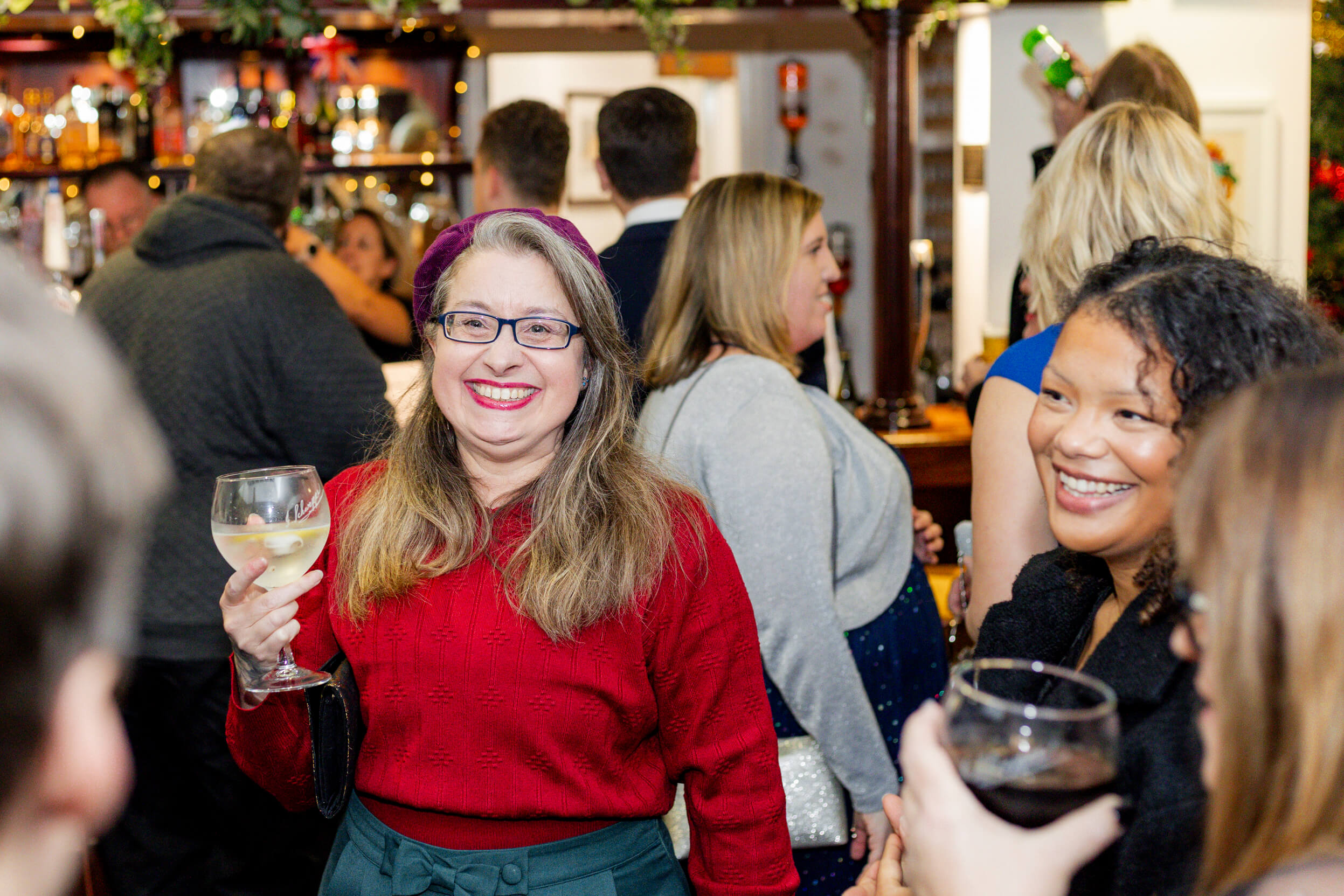 Guests smiling and chatting at the bar area, holding drinks and enjoying the festive atmosphere.