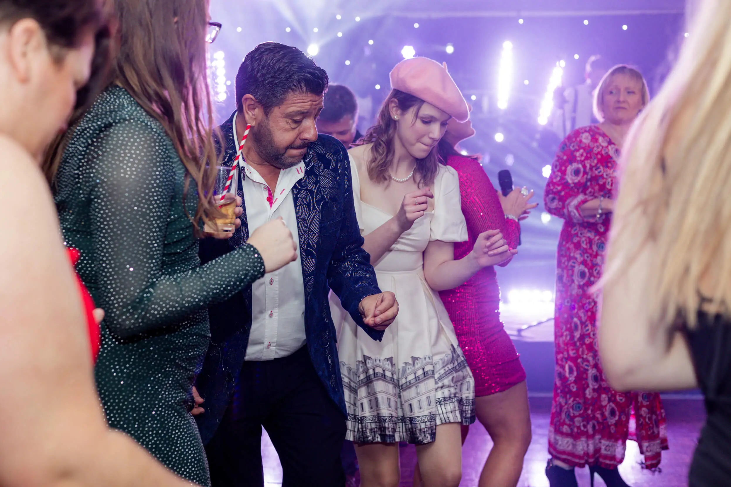 Attendees dancing and enjoying the festive atmosphere with vibrant lighting in the background.