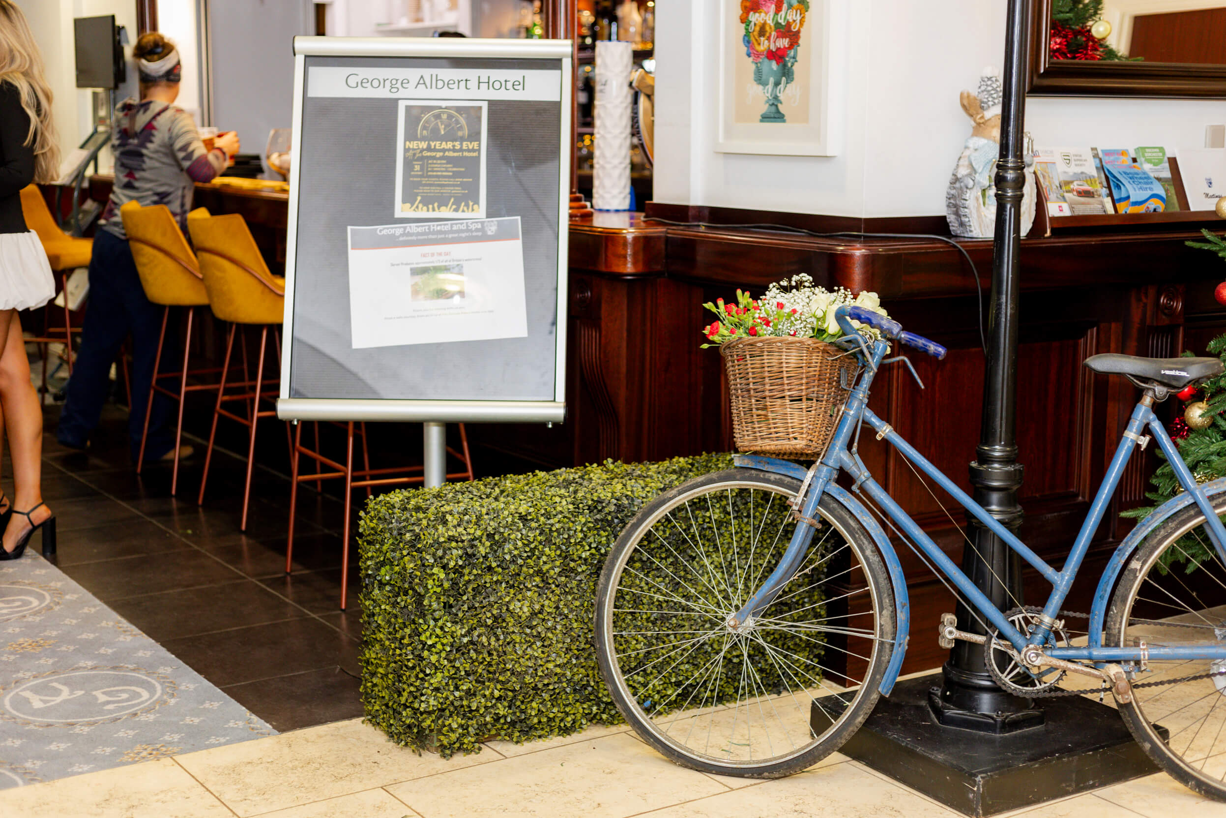 A vintage bicycle with a flower basket and a George Albert Hotel sign near the bar area, setting a charming scene.