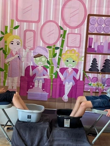 Two children enjoying a relaxing spa day with their feet in the water, smiling as they sit alongside staff members, creating a calm and enjoyable atmosphere.