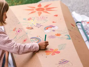 Child drawing on a plain kraft casket lid by Outside The Box Caskets.