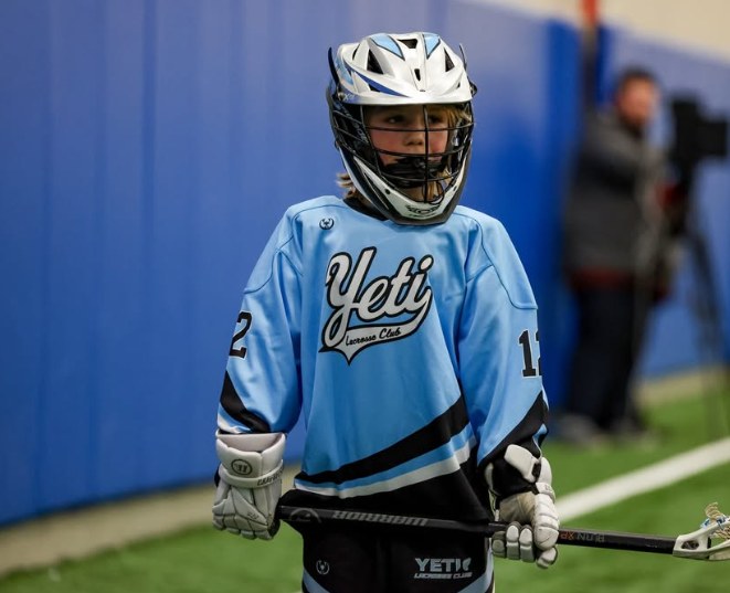 Young Yeti box player in a light blue box jersey by the boards