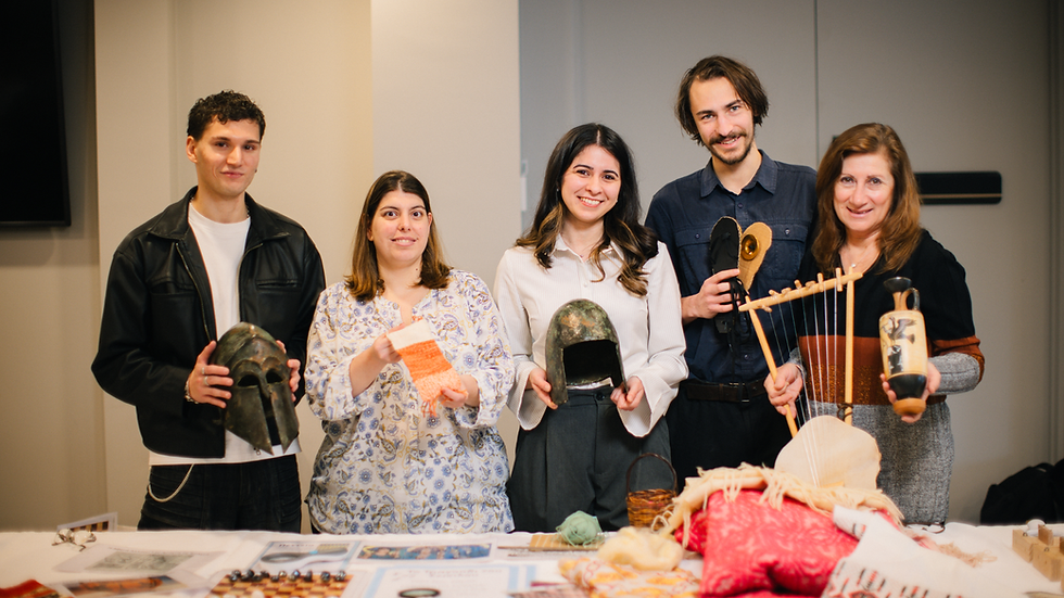 Five museum presenters stand at a table showcasing ancient artefacts and activities