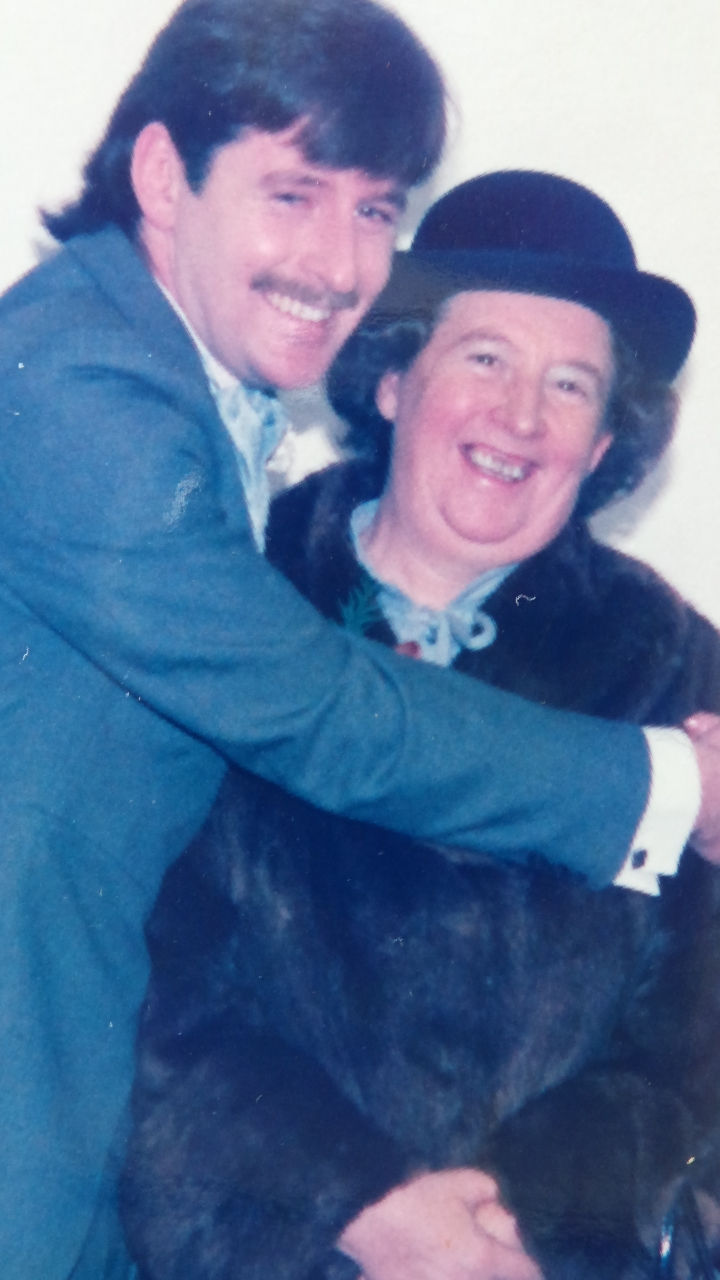 Two happy smiling people. Joe Herd, then 23, dressed in a blue morning suit on the day of his wedding squeezes his smiling mother in his arms which enfold her. Betty is wearing a dark brown fur coat and a hat.