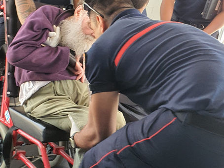 Firefighters at Noumea airport, New Caledonia, lift Dougie from an aircraft aisle wheelchair onto his own wheelchair.