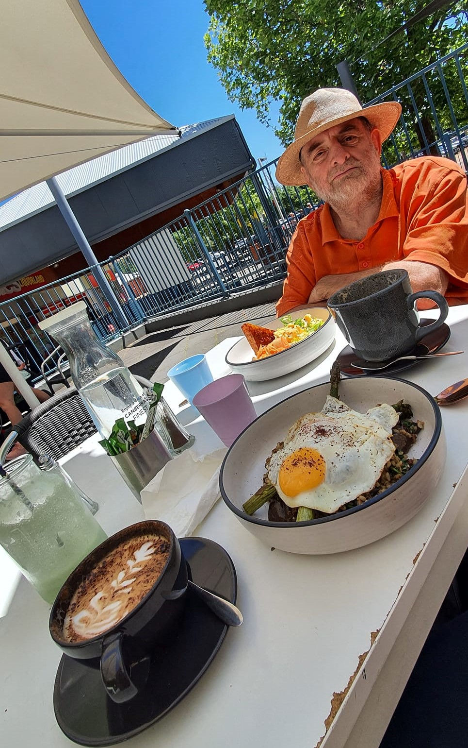 Dougie wearing his straw hat at a café table with kimchi scrambled eggs in a bowl for brunch