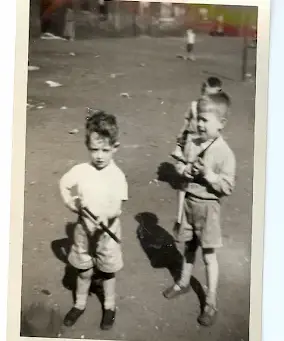 Black and white image from early 1960s. Two young boys -- one Dougie -- play with plastic rifles in a tenement back court in Glasgow's rough East End.