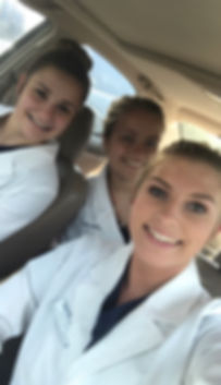 Students (from left to right) Leah Salzwedel, Addison Allen, and Maggie Jeffries smiling in their lab coats and uniforms.